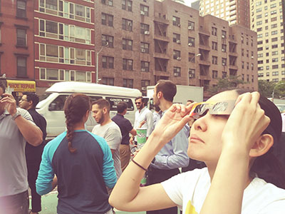 ミッドタウン45丁目で日食を見る女性=21日午後2時39分 (photo: 本紙)