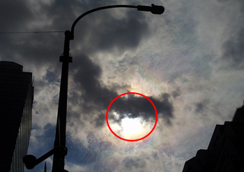 雲の隙間からわずかに見えた部分日食。スマートフォンで撮影=午後2時40分、マンハッタン区(photo: 本紙)