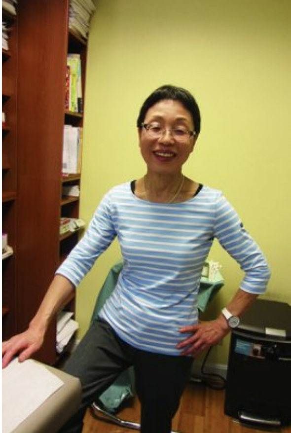 クリニックの診察室で。股関節の手術からは全快。筋トレとストレッチで、このスリムな体型をキープ！