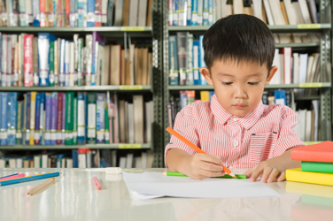 Asian Boy writing in library room school