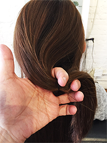 結び目を少し下にずらし、 毛束を上下に割って穴をあけます