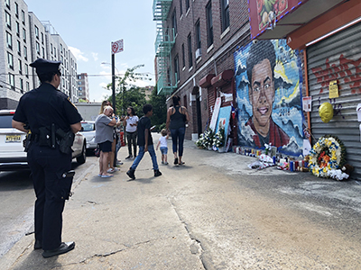 グズマン＝フェリスさんが殺された現場を訪れたブロンクス区在住のフランシスコ・サンティアゴさん（83）＝写真中央左＝は、壁画に向かって涙ながらに祈りを捧げた。「市内では殺人が多すぎる。行政、警察の抜本的な改革が必要」と話した＝12日午後、同区バスゲート街183丁目で撮影 （photo: Yuriko Anzai / 本紙）