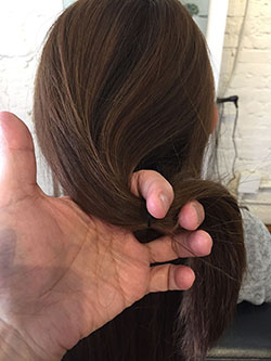 結び目を少し下にずらし、毛束を上下に割って穴をあけます